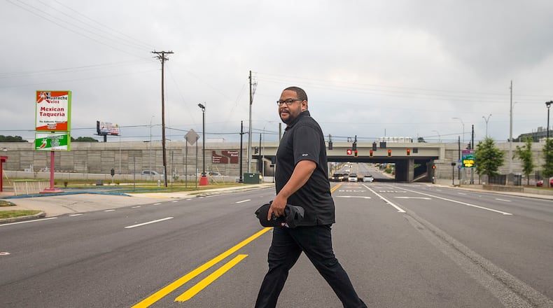 Thomas Williams crosses Roswell Road to his job at Wendy’s in Marietta on July 10. He has found it hard to find a job in his finance field, instead picking up odd jobs along the way. He and his brother currently live in an extended-stay motel. If Thomas cannot find a job in his field before the year is over, he and his brother will move to another city. (Alyssa Pointer/alyssa.pointer@ajc.com)