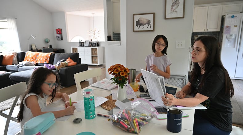 Mary Martinez helps two daughters while studying her own school work at their home in Sugar Hill on Wednesday, October 6, 2021. Martinez had been a retail sales associate before the pandemic, but she was tired of a paycheck that barely covered child care costs. She left her job and enrolled part-time at Georgia Perimeter College while her husband, a job recruiter, worked more overtime. (Hyosub Shin / Hyosub.Shin@ajc.com)