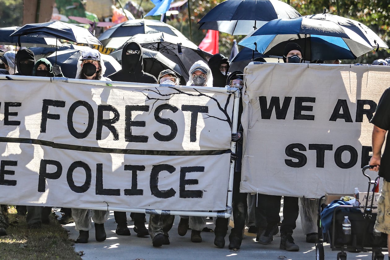 November 13, 2023 Atlanta: Protesters head through the neighborhoods to the showdown with police on Constitution Road. After a weekend of protest training, opponents of AtlantaÕs public safety training center began marching Monday morning from Gresham Park Recreation Center to the site where the $90 million facility is under construction in what organizers are calling a non-violent ÒDay of Action.Ó A few hundred people participated in the march, most wearing masks and many donned in plastic painters suits. City officials say the new center is necessary to provide world-class training to its officers and firefighters, which are currently using outdated facilities. Opponents say it will be used to further militarize police and construction will destroy swaths of one of the largest urban forests in the country. (John Spink / John.Spink@ajc.com)