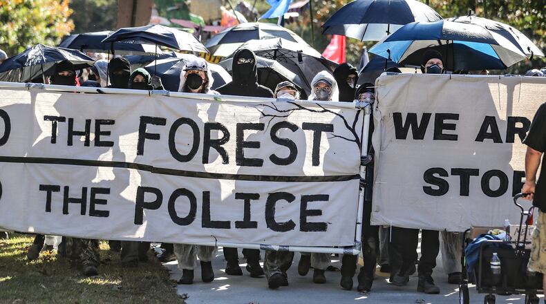 November 13, 2023 Atlanta: Protesters head through the neighborhoods to the showdown with police on Constitution Road. After a weekend of protest training, opponents of AtlantaÕs public safety training center began marching Monday morning from Gresham Park Recreation Center to the site where the $90 million facility is under construction in what organizers are calling a non-violent ÒDay of Action.Ó A few hundred people participated in the march, most wearing masks and many donned in plastic painters suits. City officials say the new center is necessary to provide world-class training to its officers and firefighters, which are currently using outdated facilities. Opponents say it will be used to further militarize police and construction will destroy swaths of one of the largest urban forests in the country. (John Spink / John.Spink@ajc.com)