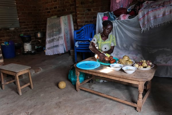 Rehema Namukose prepares a meal inside her home with clay-based earthen floors installed by EarthEnable on May 17, 2025, in Jinja, Uganda. (AP Photo/Hajarah Nalwadda)