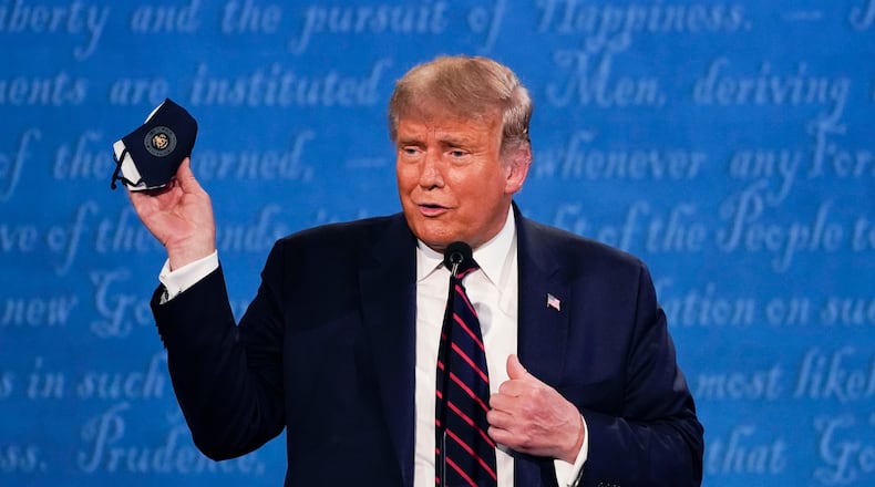 Then-President Donald Trump holds up his face mask at a Sept. 29, 2020, presidential debate at Case Western University and Cleveland Clinic in Cleveland. The U.S. death toll from the coronavirus eclipsed 400,000 in the waning hours in office for Trump. (Julio Cortez/AP)