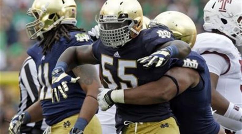 Notre Dame linebacker Prince Shembo (55) celebrates as he's hugged by teammate Stephon Tuitt after a tackle for a loss against Temple during the first half of an NCAA college football game in South Bend, Ind., Saturday, Aug. 31, 2013. (AP Photo/Michael Conroy)