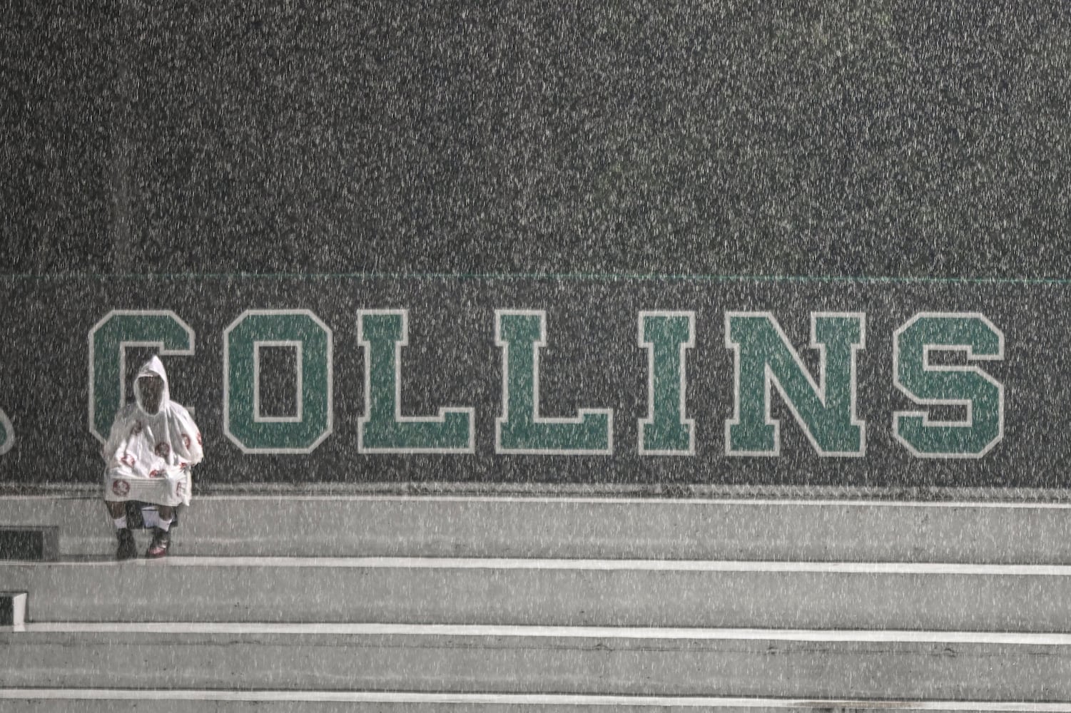 A fan waits in the bleachers during a rain delay at Collins Hill Friday, August 15, 2025. (Daniel Varnado for the AJC)