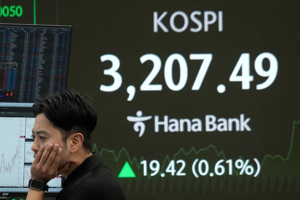 A currency trader watches monitors near a screen showing the Korea Composite Stock Price Index (KOSPI) at the foreign exchange dealing room of the Hana Bank headquarters in Seoul, South Korea, Monday, July 21, 2025. (AP Photo/Ahn Young-joon)
