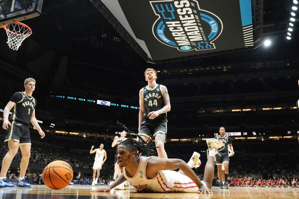 Houston's Joseph Tugler dives after a loose ball as Purdue's Caleb Furst (1) and Will Berg (44) watch during the first half in the Sweet 16 of the NCAA college basketball tournament Friday, March 28, 2025, in Indianapolis. (AP Photo/Michael Conroy)