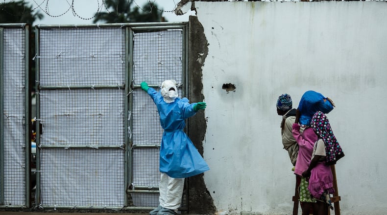 The David J. Sencer CDC Museum hosts a comprehensive exhibition featuring photographs, artifacts and documentation dedicated to the global health crisis of Ebola. In this image, a health care worker wearing protective garments opens the door for an ambulance exiting a Monrovia, Liberia, clinic. CONTRIBUTED BY MORGANA WINGARD, COURTESY OF USAID