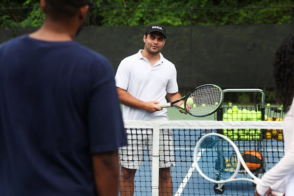Valentino Caratini prepares to serve balls to students during a tennis clinic. Caratini began working as a tennis coach post-graduation when he began to notice a gap for players struggling to find partners and coaches. (Abbey Cutrer/AJC)