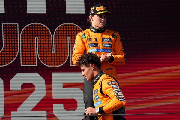 McLaren driver Lando Norris of Britain walks past McLaren driver Oscar Piastri of Australia on the podium after placing second at the Italian Emilia Romagna Formula One Grand Prix, at the Enzo and Dino Ferrari racetrack in Imola, Italy, Sunday, May 18, 2025. (AP Photo/Luca Bruno)