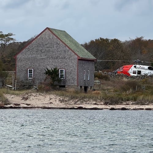 A U.S. Coast Guard helicopter approaches Naushon Island, Mass. Wednesday, Oct. 22, 2025, where a couple and their adult son were rescued two days after their boat caught fire and they swam to shore. (U.S. Coast Guard via AP)