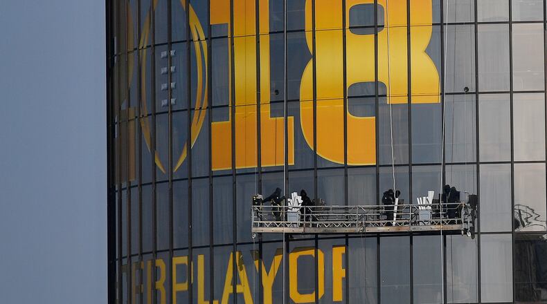 Workers place signage on an Atlanta hotel Wednesday to celebrate the College Football Playoff championship game being played here.