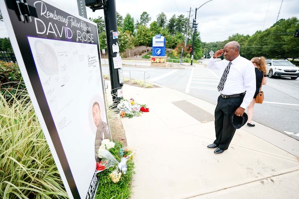DeKalb County resident Willie Anthony salutes the memorial of DeKalb County police Officer David Rose, 33, outside the headquarters of the Centers for Disease Control and Prevention on Sunday, Aug. 10, 2025. Rose died in the line of duty while responding to a shooter who directed bullets at the CDC on Friday. (Miguel Martinez/AJC)