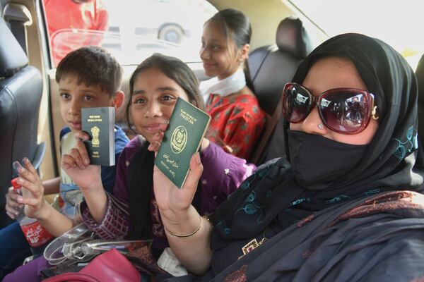 Pakistani national Khalida Hanif, right, and her Indian children display their passports on their return from Pakistan at the Attari-Wagah border between India and Pakistan, near Amritsar, India, Tuesday, April 29, 2025. (AP Photo/Prabhjot Gill)