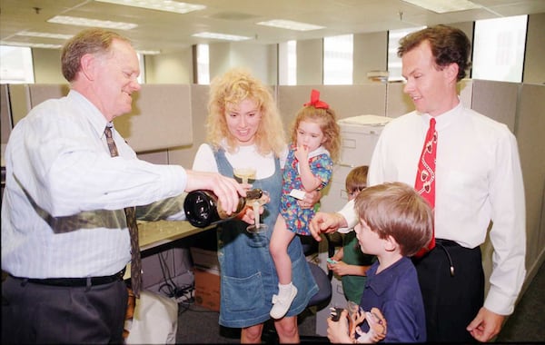 Atlanta Journal-Constitution editor Ron Martin (left) pours champagne for editorial cartoonist Mike Luckovich to celebrate winning the Pulitzer Prize. Luckovich's wife, Margo, and children Micaela, 3; Mickey, 6 and John, 8, joined in the celebration. 