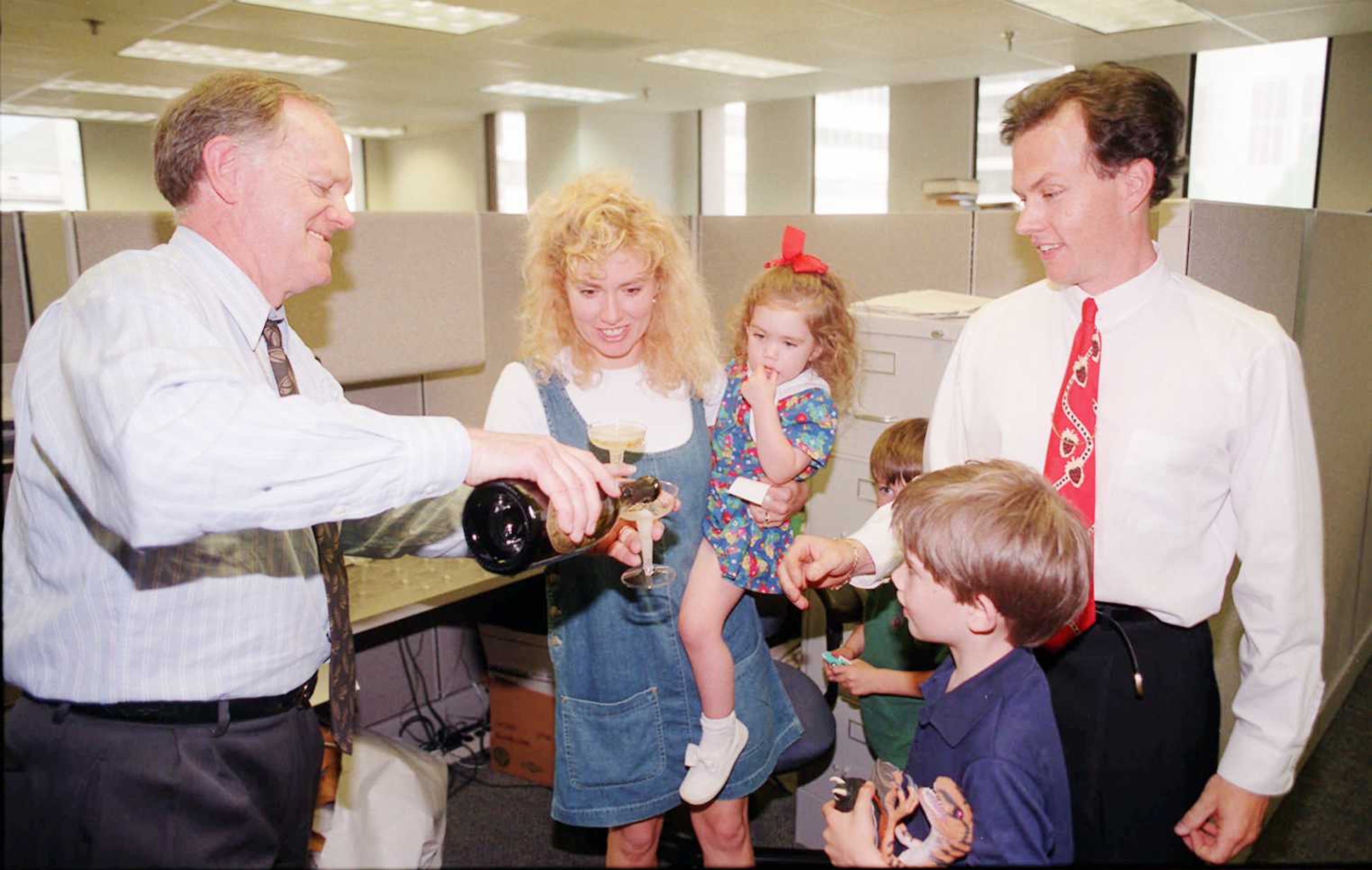 Atlanta Journal-Constitution editor Ron Martin (left) pours champagne for editorial cartoonist Mike Luckovich to celebrate winning the Pulitzer Prize. Luckovich's wife, Margo, and children Micaela, 3; Mickey, 6 and John, 8, joined in the celebration.