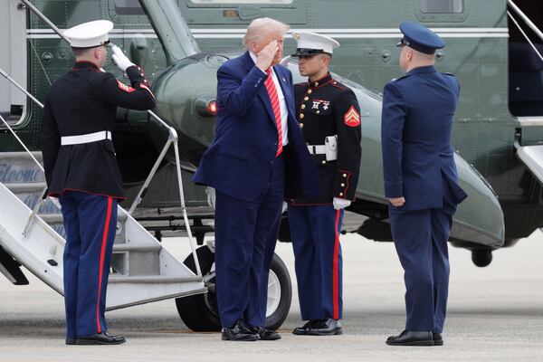 President Donald Trump, center, is greeted by Col. Paul Pawluk, Vice Commander, 89th Airlift Wing, right upon his arrival at Joint Base Andrews, Md., Friday, May 30, 2025. (AP Photo/Luis M. Alvarez)