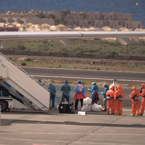 Passengers stand next to a Spanish government plane after disembarking from the hantavirus-stricken cruise ship MV Hondius at the airport in Tenerife, Canary Islands, Spain, Sunday, May 10, 2026. (AP Photo/Arturo Rodriguez)