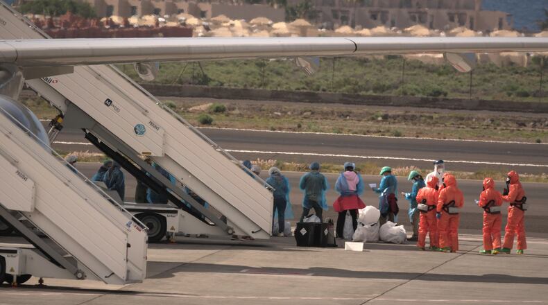 Passengers stand next to a Spanish government plane after disembarking from the hantavirus-stricken cruise ship MV Hondius at the airport in Tenerife, Canary Islands, Spain, Sunday, May 10, 2026. (AP Photo/Arturo Rodriguez)
