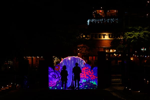 Attendees interact with a display at the Illumine exhibit at Oakland Cemetery in Atlanta on April 16, 2026. (Arvin Temkar/AJC)