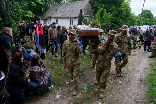 An honor guard carries the coffin of Dmytro Shapovalov, a Ukrainian serviceman, during his funeral ceremony in Yosypivka village, Vinnytsia region, Ukraine, on Friday, June 13, 2025. (AP Photo/Evgeniy Maloletka)