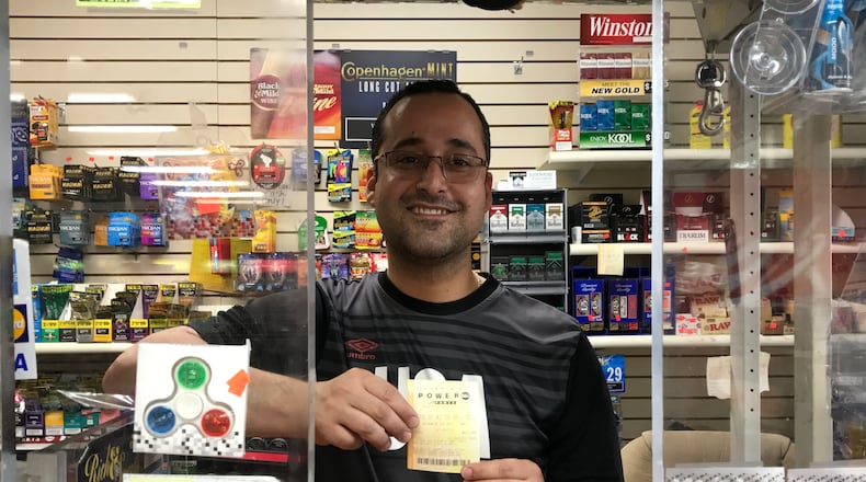 Hamid Rafie, who works at Akers Mill Food Mart, holds a Powerball ticket. Is it the winner? SHEILA POOLE / SHEILA .POOLE@AJC.COM