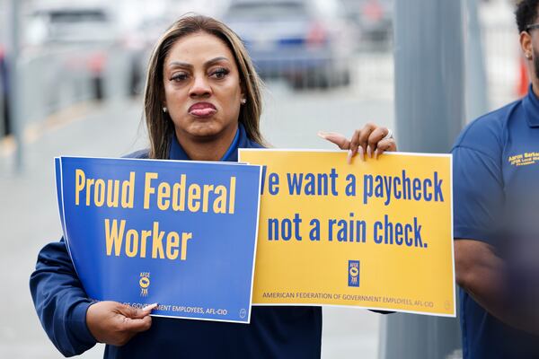 Melanie Thurston, chief steward for American Federation of Government Employees Local 554, holds signs during a news conference at Hartsfield-Jackson International Airport on Monday, March 16, 2026. (Arvin Temkar/AJC)