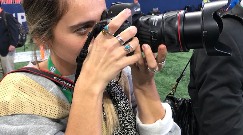 UGA intern Chamberlain Smith shoots a photo of Georgia coach Kirby Smart coming onto the field at Mercedes-Benz Stadium on Saturday. It's her first game back since she was injured in a sideline collision at Auburn on Nov. 16. (Chip Towers/ctowers@ajc.com)