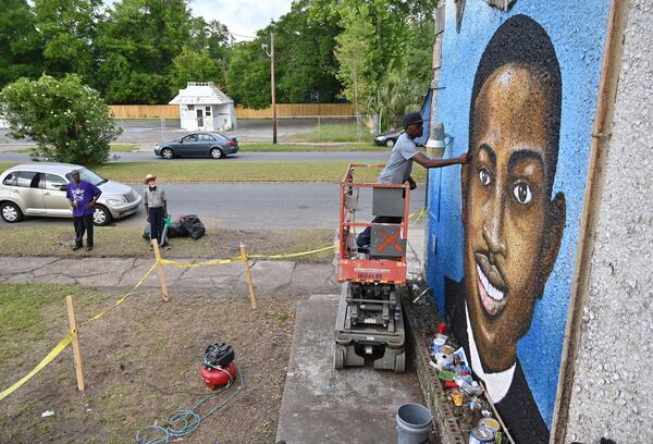 Miami-based artist Marvin Weeks, who is originally from Brunswick, works on a large mural in tribute to Ahmaud Arbery on the side of a building which will soon be the site of the Brunswick African American Cultural Center in Brunswick on Friday, May 15, 2020. Arbery was shot Feb. 23 as he jogged through Satilla Shores, a mostly white community a few miles from his Brunswick home. (Hyosub Shin/AJC 2020)