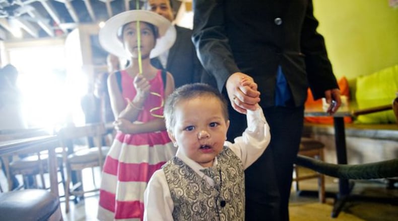 Bounkham Phonesavanh holds his mother Alecia’s hand as they walk to their table during a farewell breakfast at Delightful Eatz in Atlanta on July 2, 2014. JONATHAN PHILLIPS / FOR THE AJC