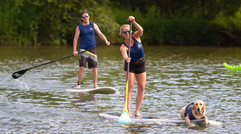 Caroline Slone, crosses the finish line with her dog Burkley during the 8th annual Stand Up for the Hooch at Morgan Falls Overlook Park in Sandy Springs in June 2019. Sandy Springs continues to seek public input on development plans for Morgan Falls, Roswell Road at Azalea Drive and Crooked Creek Park. The latest concepts were generated from residents' comments during an August virtual open house for the Sandy Springs Riverfront Vision Plan, said Dan Coffer, a city spokesman.  STEVE SCHAEFER / SPECIAL TO THE AJC