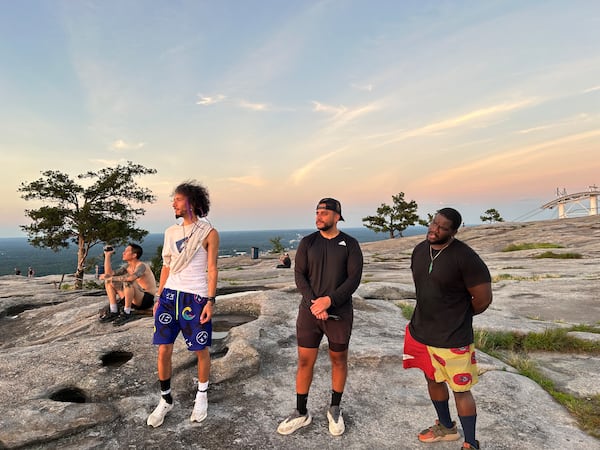 Friends Isaiah Ramirez (from left), Faris Mousa and Kelechi Emeonye take in the sunset atop Stone Mountain on Friday, June 20, 2025. (Thomas Lake/AJC)