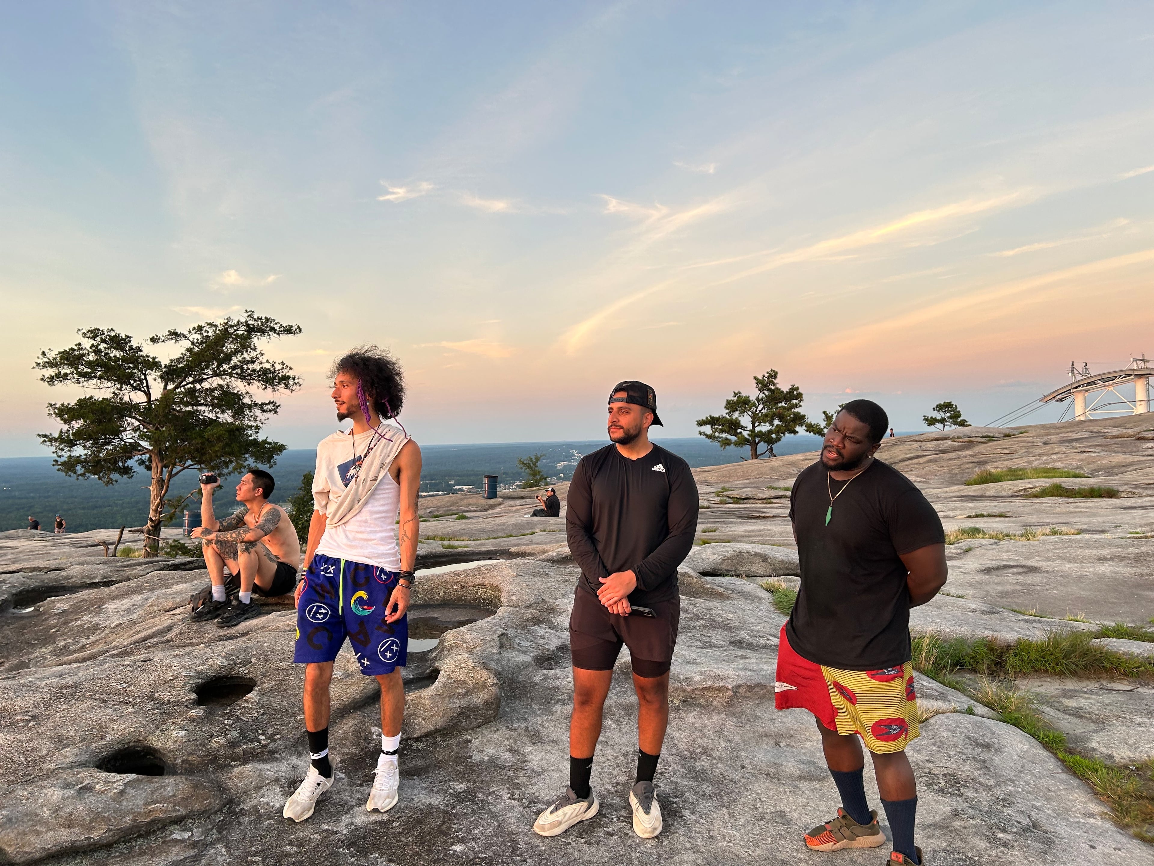 Friends Isaiah Ramirez (from left), Faris Mousa and Kelechi Emeonye take in the sunset atop Stone Mountain on Friday, June 20, 2025. (Thomas Lake/AJC)