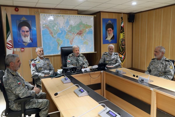 In this photo released on Monday, 23, 2025, by Iranian army press service, Iran's army commander-in-chief Gen. Amir Hatami, center, accompanied by high ranked army commanders, speaks in a video call with top commanders of the army, in Zolfaghar central headquarters, Iran, as portraits of the late revolutionary founder Ayatollah Khomeini, left, and Supreme Leader Ayatollah Ali Khamenei hang on the wall. (Iranian Army Press Service via AP)
