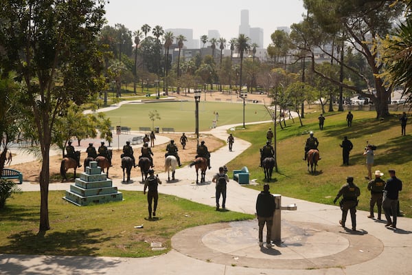Federal agents ride on horseback at MacArthur Park Monday, July 7, 2025, in Los Angeles. (AP Photo/Damian Dovarganes)
