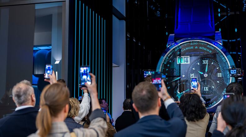 Visitors take photos with their smartphones of a watch at the German watch manufacturer A. Lange & Shone stand, during the opening day of the "Watches and Wonders Geneva" luxury watch fair, in Geneva, Switzerland, Tuesday, April 14, 2026. (Salvatore Di Nolfi/Keystone via AP)