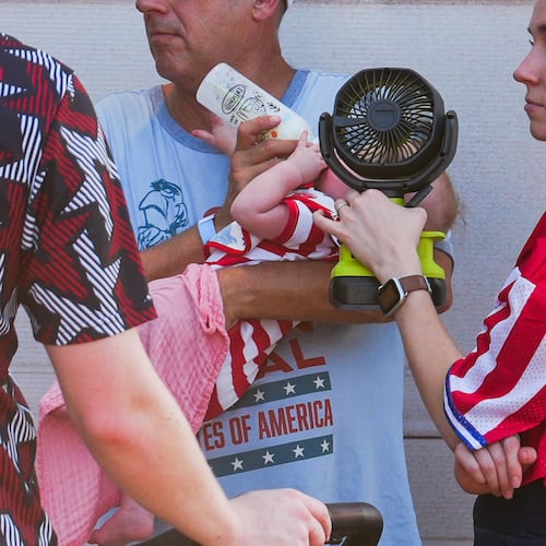 A woman holds a fan in front of a bottle-fed baby at the Great American State Fair, during an extreme heat wave, Friday, July 3, 2026, on the National Mall in Washington. (AP Photo/Julia Demaree Nikhinson)