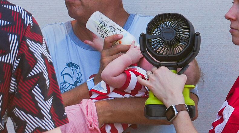 A woman holds a fan in front of a bottle-fed baby at the Great American State Fair, during an extreme heat wave, Friday, July 3, 2026, on the National Mall in Washington. (AP Photo/Julia Demaree Nikhinson)