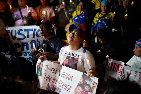People with photos of their relatives who were deported from the U.S. to a prison in El Salvador, for being alleged members of the Tren de Aragua gang, cry and pray outside El Salvador's embassy in Caracas, Venezuela, April 2, 2025. (AP Photo/Ariana Cubillos)