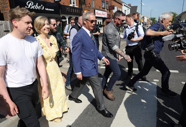Reform UK leader Nigel Farage crosses the road with Reform UK mayoral candidate Andrea Jenkyns as they campaign together in Scunthorpe, England, Tuesday, April 29, 2025. (AP Photo/Darren Staples)