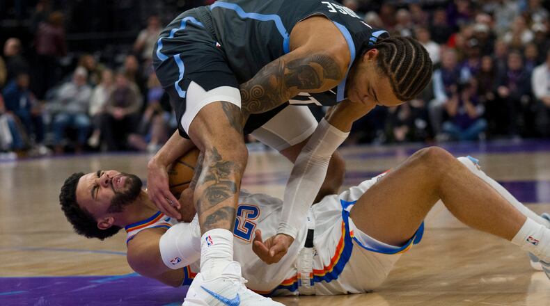 Utah Jazz guard Keyonte George, top, and Oklahoma City Thunder guard Ajay Mitchell (25) fight for the ball during the first half of an NBA basketball game Sunday, Dec. 7, 2025, in Salt Lake City. (AP Photo/Bethany Baker)
