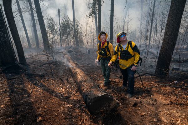 Firefighters watch a water helicopter as they work to control the Black Cove Fire Wednesday, March 26, 2025, in Saluda, N.C.. (AP Photo/Allison Joyce)