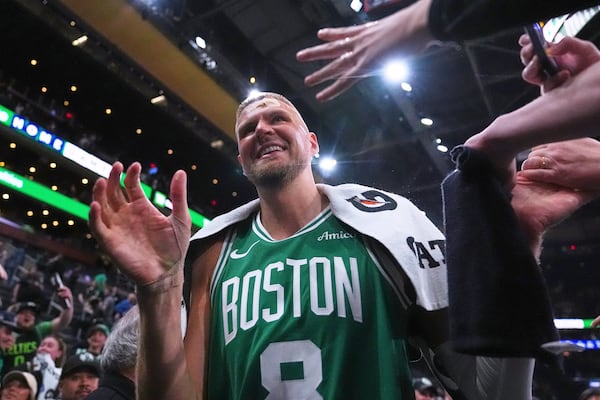 With his head bandaged after an injury, Boston Celtics center Kristaps Porzingis (8) is congratulated by fans after defeating the Orlando Magic in game 2 of a first-round NBA playoff basketball series, Wednesday, April 23, 2025, in Boston. (AP Photo/Charles Krupa)