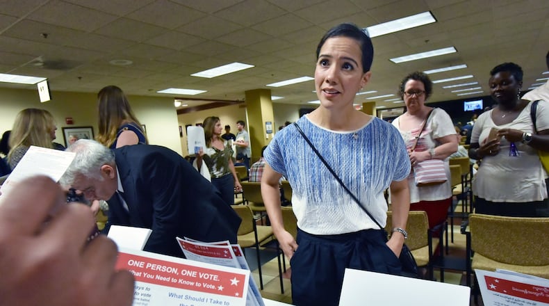 Newly naturalized citizen Perla Freed, originally from Honduras, completes her voting registration helped by Samuel Aguilar (left, showing hand), with Georgia Association of Latino Elected Officials, after her naturalization ceremony at the USCIS Atlanta Field Office on Friday, June 17, 2016. HYOSUB SHIN / HSHIN@AJC.COM