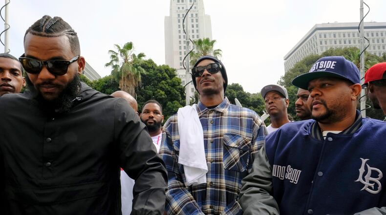 Rappers The Game, left, and Snoop Dogg, center, appear at a peaceful unification march outside of the graduation ceremony for the latest class of Los Angeles Police recruits in Los Angeles, Friday, July 8, 2016. Snoop shook hands with police officials and told reporters he hoped his presence would help reintroduce the black community to the Police Department and open a dialogue. The gathering comes a day after the shooting deaths of multiple police officers in Dallas on Thursday night. (AP Photo/Richard Vogel)