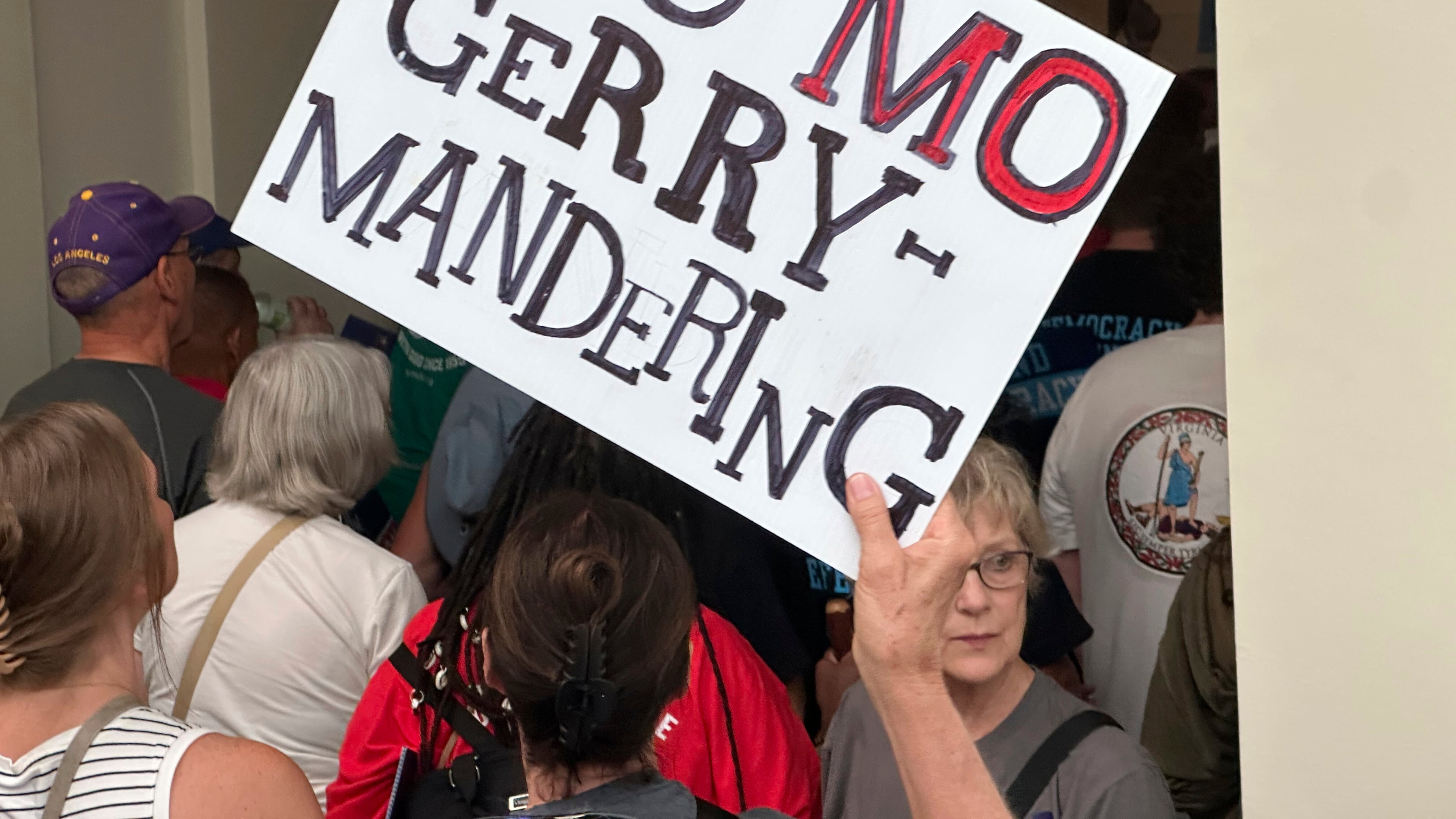 An opponent of a plan to redraw Missouri's U.S. House districts raises a sign against gerrymandering in a hallway outside the state Senate chamber in Jefferson City, Mo., Wednesday, Sept. 10, 2025. (AP Photo/David A. Lieb)