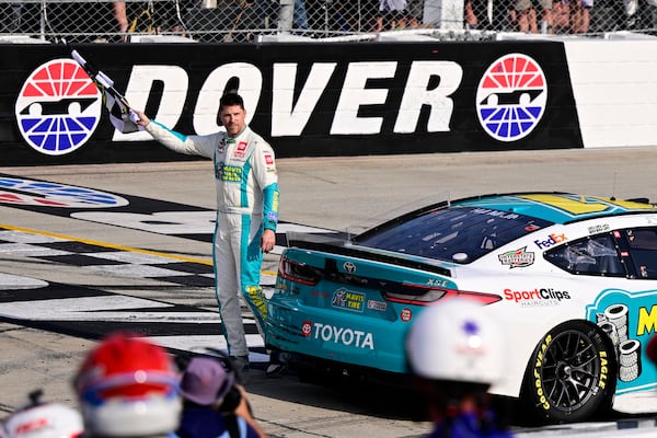 FILE - Denny Hamlin celebrates with the checkered flag after winning a NASCAR Cup Series auto race at Dover Motor Speedway, Sunday, April 28, 2024, in Dover, Del. (AP Photo/Derik Hamilton, File)