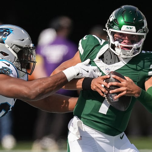 New York Jets quarterback Justin Fields (7) tries to avoid a tackle by Carolina Panthers linebacker D.J. Wonnum (98) during the first quarter of an NFL football game, Sunday, Oct. 19, 2025, in East Rutherford, N.J. (AP Photo/Seth Wenig)