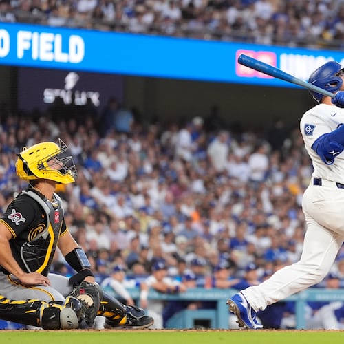 Los Angeles Dodgers' Max Muncy, right, hits a two-run home run as Pittsburgh Pirates catcher Rafael Flores Jr. watches during the first inning of a baseball game Friday, Aug. 21, 2026, in Los Angeles. (AP Photo/Mark J. Terrill)