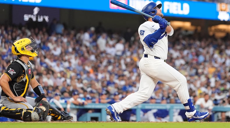 Los Angeles Dodgers' Max Muncy, right, hits a two-run home run as Pittsburgh Pirates catcher Rafael Flores Jr. watches during the first inning of a baseball game Friday, Aug. 21, 2026, in Los Angeles. (AP Photo/Mark J. Terrill)