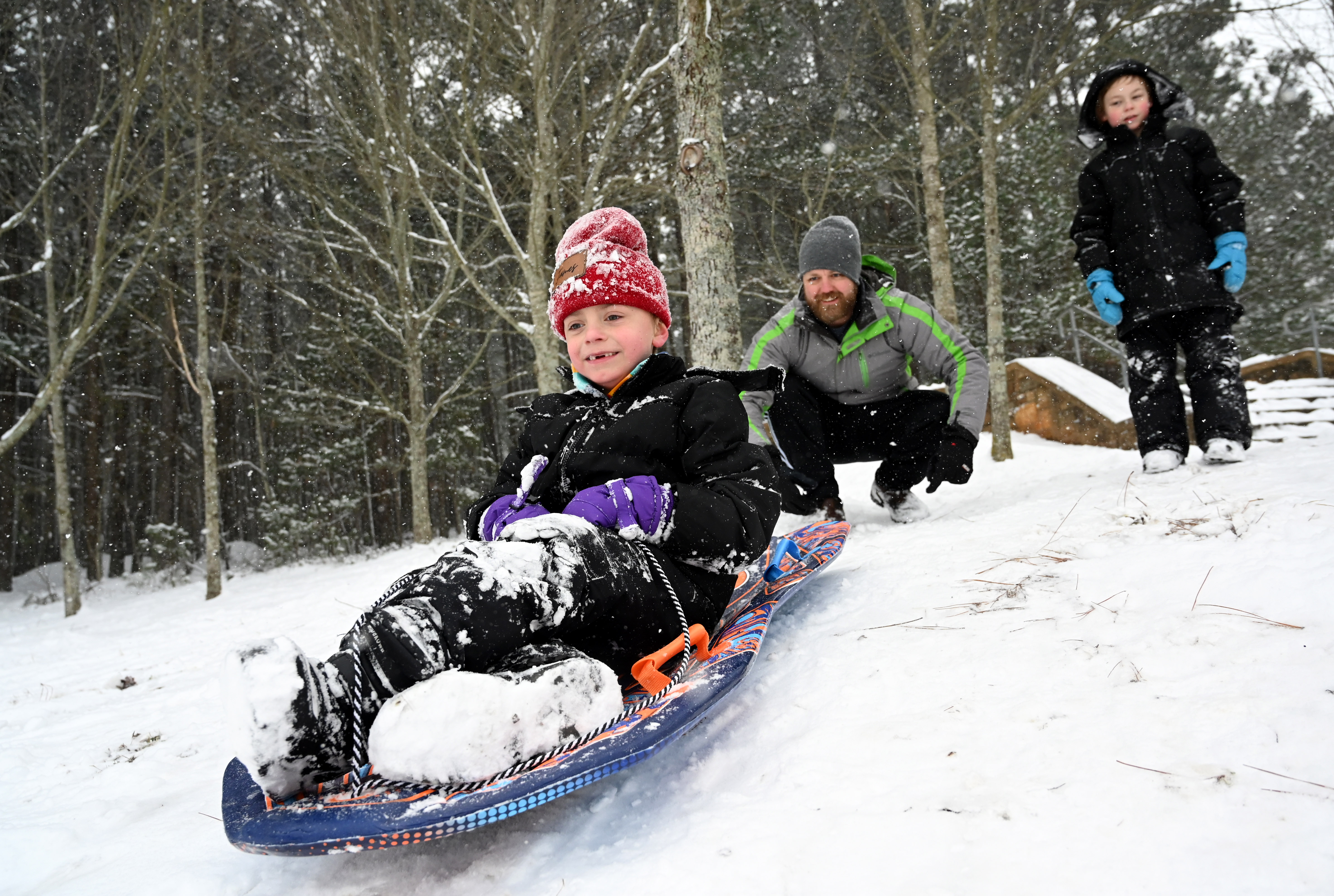 James Myers, 7, sleds down a hill Saturday as his father Lee Myers pushes him at Little Mulberry Park in Dacula, Georgia, north of Atlanta. (Hyosub Shin/AJC)